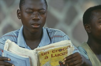 CONGO, Education, Boy reading from French book.