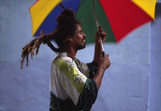 CUBA, Havana, "Rastafarian man on stilts, with umbrella as part of street parade "