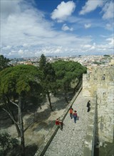 PORTUGAL, Lisbon, Tourist visitors on fortified walls of Castelo de Sao Jorge  with city stretched