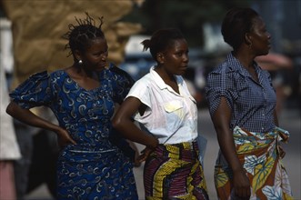 CONGO, Kinshasa, Three women wearing brightly patterned textiles.