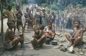 CONGO, Ituri Forest, Pygmy group in village clearing surrounded by thatched huts.