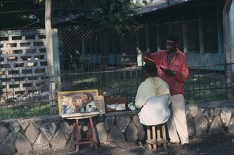 CONGO, Kinshasa, Street barber with customer.