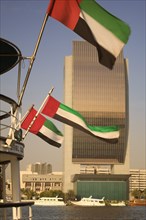 UAE, Dubai, The National Bank with Emirates national flags flying from the stern of a boat in the