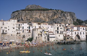 ITALY, Sicily, Palermo, Cefalu. View across the sea with people swimming in the water and