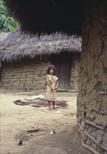 COLOMBIA, Santa Marta, Sierra Nevada, "Young Cogi girl holding cotton yarn, standing in-between two