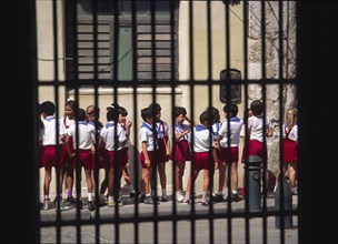 CUBA, Havana, "School children waiting in a line, viewed through window of a colonial building."