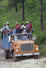 GUATEMALA, Highlands, Ford truck full of campesino men climbing a steep incline.