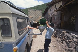 PERU, Cajamarca, Purchasing gasoline in the highlands. Man pouring gas through a funnel into van.