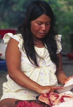 PERU, Departamento de Ucayali, Sepahua, Machiguenga indian woman preparing meat.