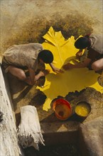 MOROCCO, Fes, Chouwara Tanneries.  Looking down on two men with stretched yellow hide.
