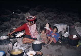 PERU, Andes, Sacred Valley, Cancha Cancha. Quechuan Indian family cooking inside their house.