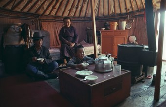 MONGOLIA, People, Family, Interior of yurt with family having meal in Summer.