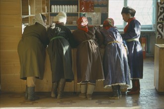 MONGOLIA, People, Group of women leaning on wooden shop counter to talk.
