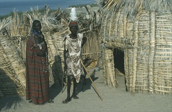 KENYA, Lake Turkana, "Turkana tribe, two men standing outside a traditional hut made from dry fan