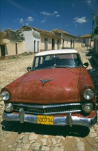 CUBA, Trinidad, Old red  American car in cobbled street.