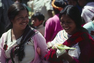 GUATEMALA, Chichicastenango, "Two indegenous women smiling, one holding sweetcorn."