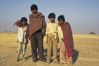 INDIA, Rajastan, "Group of young boys in the desert, some with blankets round them."
