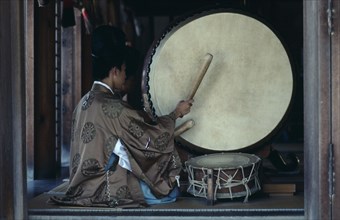 JAPAN, Honshu, Shimane, Izumo.  Priests striking large drum during worship at Izumo-Taisha one of