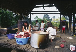PERU, Departamento de Ucayali, Sepahua, Machiguenga mother with family preparing food.