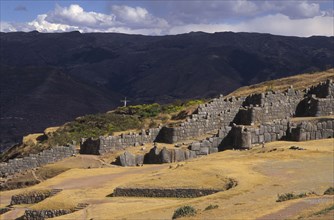 PERU, Cuzco, "Sacsayhuaman inca site, people walking round the old walls and a cross in the