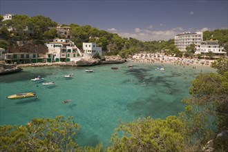 SPAIN, Balearic Islands, Mallorca, "Cala Santany, View of the beach with boats on the clear water."