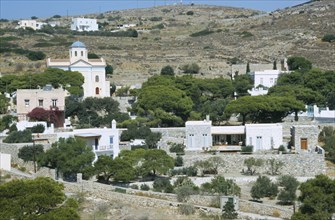 GREECE, Cyclades Islands, Syros, Ano Mana village on a mountain side with trees.
