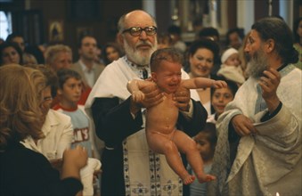 GREECE, Cyclades Islands, Syros, "A Greek orthodox christening, the child being held up by the