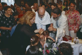 GREECE, Cyclades Islands, Syros, "A Greek orthodox christening, the child being held and water