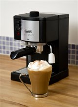 FOOD & DRINK, Coffee, Domestic Coffee machine on wooden kitchen worktop with a cup of cappuccino in