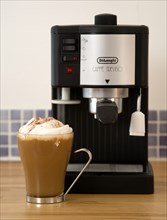 FOOD & DRINK, Coffee, Domestic Coffee machine on wooden kitchen worktop with a cup of cappuccino in