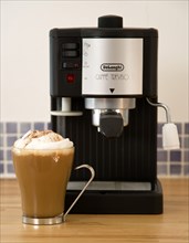 FOOD AND DRINK, Coffee, Domestic Coffee machine on wooden kitchen worktop with a cup of cappuccino