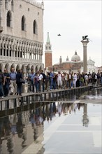 ITALY, Veneto, Venice, Aqua Alta High Water flooding in St Marks Square with tourists walking on
