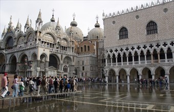 ITALY, Veneto, Venice, Aqua Alta High Water flooding in St Marks Square with tourists walking on