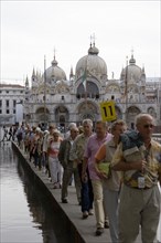 ITALY, Veneto, Venice, Aqua Alta High Water flooding in St Marks Square A party of tourists walking