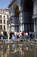 ITALY, Veneto, Venice, Aqua Alta High Water flooding in St Marks Square with tourists queuing on