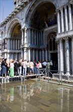 ITALY, Veneto, Venice, Aqua Alta High Water flooding in St Marks Square with tourists queuing on