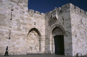 ISRAEL, Jerusalem, The Jaffa Gate. Orthodox Jewish man walking next to stone walls towards gate