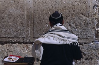 ISRAEL, Jerusalem, A Jewish man wearing a traditional prayer shawl praying at the Western Wall.