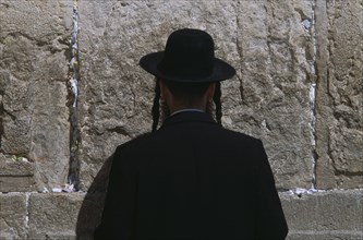 ISRAEL, Jerusalem, An Ultra Orthodox Jewish Man wearing a black hat and coat praying at the Western