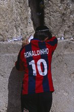 ISRAEL, Jerusalem, An Israeli boy wearing a Ronaldinho football shirt praying at the Western Wall.