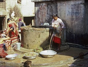 NEPAL, Khokana, One of the villagers drawing water and others washing their hair at the village