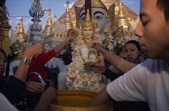 MYANMAR, Yangon, People making offerings of flowers and water at shrine in Shwedagon Pagoda.