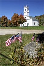 USA, New Hampshire, Autumn foliage, White wooden church and autumnal trees with American Stars &