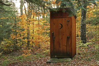 USA, New Hampshire, Sullivan, Outhouse amidst autumnal foliage.
