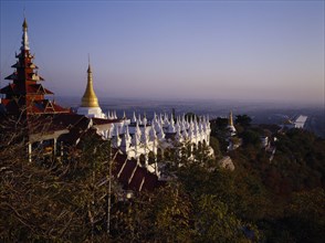 MYANMAR, Mandalay, View south from Mandalay Hill over temple stupas and pagoda style roof.