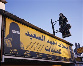 BAHRAIN, Muharraq Island, Markets, Shopfront sign with images of a woman in a veil and a woman in a