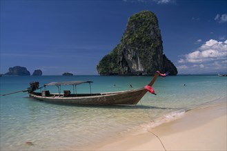 THAILAND, Krabi Province, Ao Phra Nang, Longtail boat moored in shallow water beside golden sand
