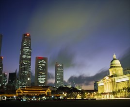 SINGAPORE, Raffles Place, Illuminated skyline of Raffles Place at dusk from Padang.