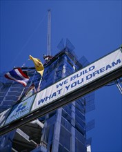 THAILAND, Bangkok, Looking up at sign ‘We Build What You Dream’ with high rise building under
