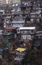 INDIA, West Bengal, Darjeeling, Poor quality housing on steep hillside strewn with litter.